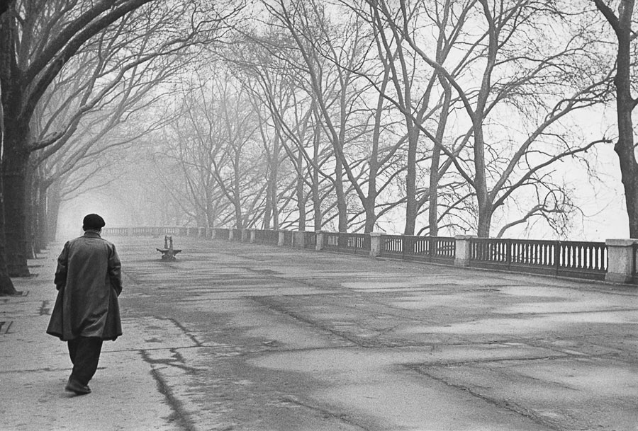 man links in beeld op de rug gezien loopt over straat in Parijs, zwart-wit